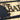 Close up of pine trees on our rectangular family name custom metal sign, in matte black powder coat.
