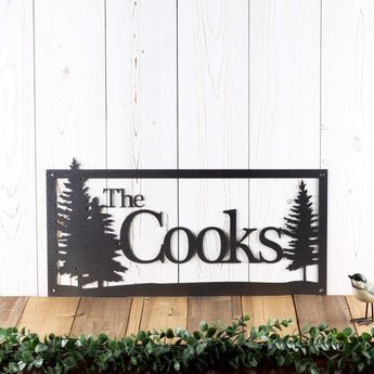 Rectangular personalized family last name metal sign with pine trees, in silver vein powder coat. 