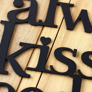 Close up of lettering on our Always Kiss Me Goodnight metal wall decor, in matte black powder coat. 