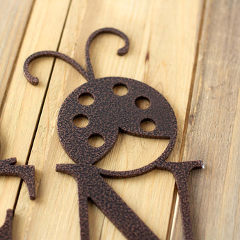 Close up of copper vein powder coat on our garden name sign with ladybug.