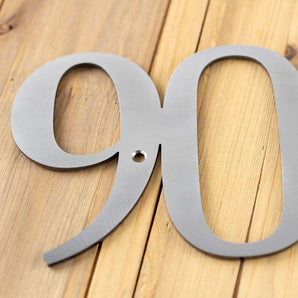 Close up of 3 digit metal house number sign, in raw steel.