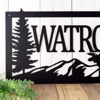 Close up of metal family name sign with mountains, in matte black powder coat.