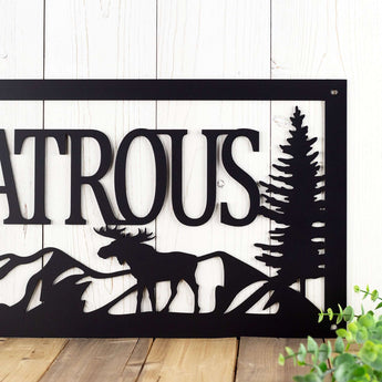Close up of metal family name plaque with moose and mountains, in matte black powder coat.