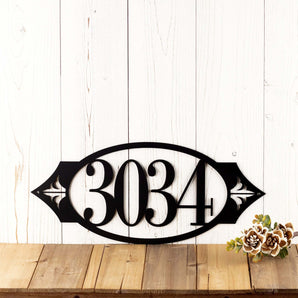 Oval 4 digit metal house number sign with fleur de lis, in matte black powder coat.