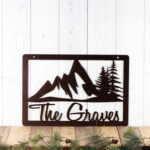 Rectangular personalized family name metal sign with mountains and pine trees, in copper vein powder coat.