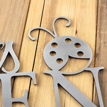 Close up raw steel on our metal garden name sign with a ladybug.