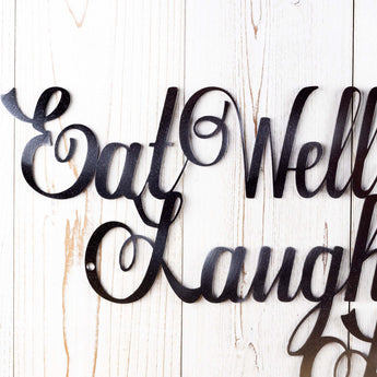 Close up of Eat Well Laugh Often Love Much script metal sign, in raw steel.