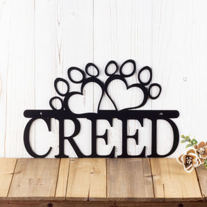 Personalized dog name metal sign with paw prints, in matte black powder coat.