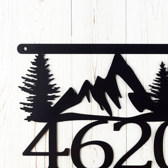 Close up of mountains and pine trees on our hanging metal house number plaque, in matte black powder coat.