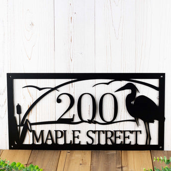 Rectangular metal address sign with great blue heron, cattails, and and sunset lake scene, in matte black powder coat.