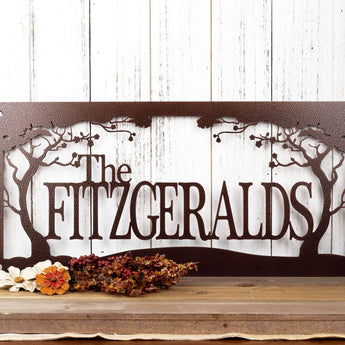 Rectangular metal family name sign with cherry trees, in copper vein powder coat. 