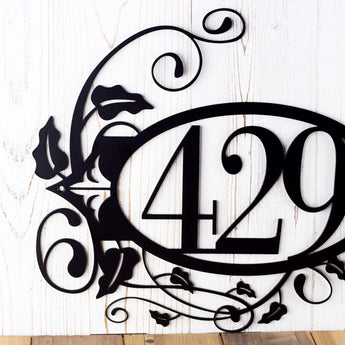 Close up of 3 digit metal house number sign with vines and fleur de lis, in matte black powder coat.