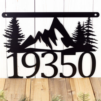 Close up of mountains and trees on our 5 digit hanging metal house number sign, in matte black powder coat.