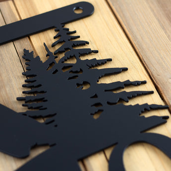 Close up of matte black powder coat on our hanging metal house number sign with pine trees and mountains. 