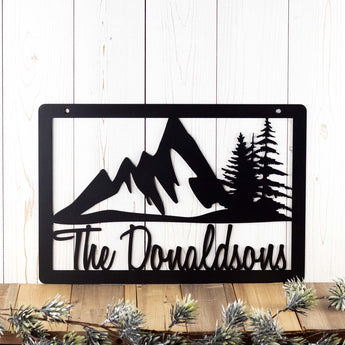 Rectangular personalized family name metal plaque with mountains and pine trees, in matte black powder coat.