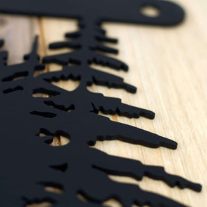 Close up of matte black powder coat on our hanging metal house number sign with pine trees and mountains.