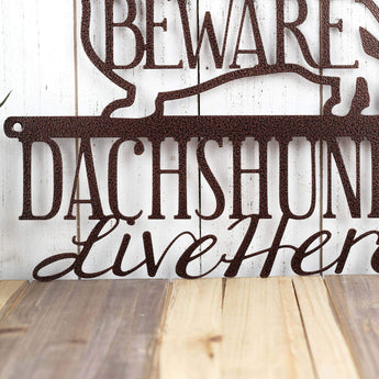 Close up of wording on our Dachshunds Live Here metal plaque, in copper vein powder coat.