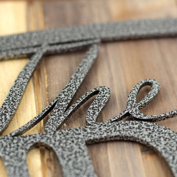Close up of silver vein powder coat on our oval outdoor metal family name sign.