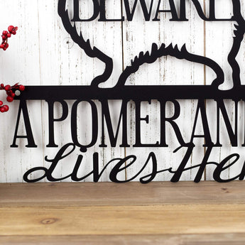 Close up of A Pomeranian Lives Here wording on our Pomeranian metal sign, with Beware, in matte black powder coat. 