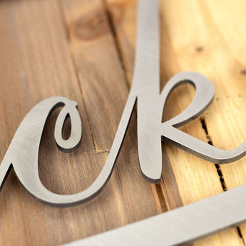 Close up of raw steel on our metal oval family sign with script font.