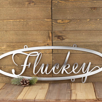 Oval family last name metal sign with script font, in raw steel. 