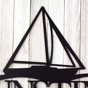 Close up of a sailboat on our personalized family name metal sign, in matte black powder coat. 