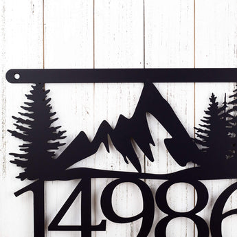 Close up of mountains and trees on our 5 digit hanging metal house number sign, in matte black powder coat.