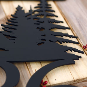 Close up of matte black powder coat on our hanging metal house number sign with pine trees and mountains. 
