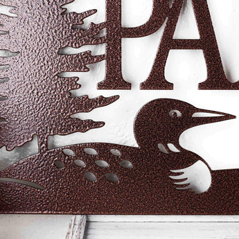 Close up of loon silhouette on our custom family name metal plaque, in copper vein powder coat. 