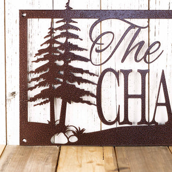 Close up of pine trees on our personalized family name sign, in copper vein powder coat.