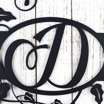 Close up of our metal monogram sign with vines surrounding the letter, D, in matte black powder coat.