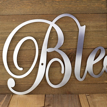 Close up of Blessings metal wall decor with a script font, in raw steel. 