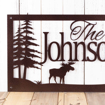 Close up of rectangular custom metal sign with moose and pine trees, in copper vein powder coat.