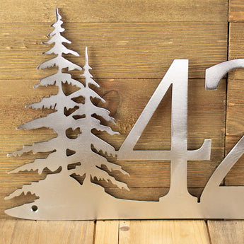 Close up of pine trees on our 2 digit metal house number sign, in raw steel. 
