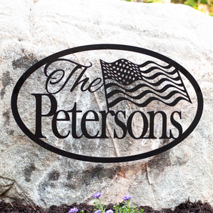 Personalized oval family name metal sign with American flag, in matte black powder coat.