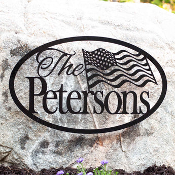 Personalized oval family name metal sign with American flag, in matte black powder coat.