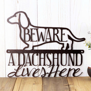 Close up of A Dachshund Lives Here metal wall art, with Beware, in copper vein powder coat.