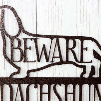 Close up of Beware on our Dachshund Live Here metal sign, in copper vein powder coat.