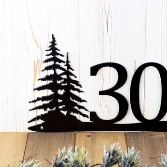 Close up of pine trees on our 3 digit metal house number sign, in matte black powder coat.