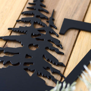 Close up of matte black powder coat on our 4 digit metal house number plaque with pine trees.