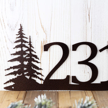Close up of pine trees on our 3 digit metal house number sign, in copper vein powder coat.