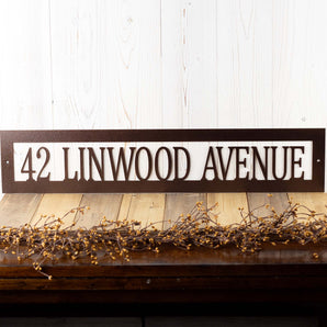 Rectangular metal address sign in copper vein powder coat.  Placed against a white wood wall.