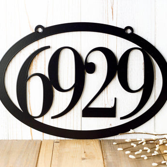 Close up of 4 digit oval metal house number sign, in matte black powder coat.