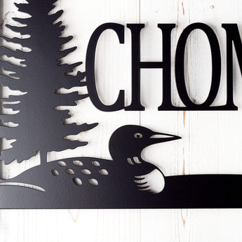 Close up of loon silhouette on our custom family name metal plaque, in matte black powder coat. 