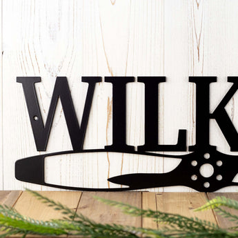 Close up of pilot family name metal sign with propeller, in matte black powder coat. 