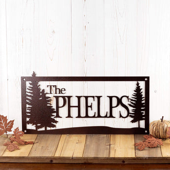 Personalized rectangular family name metal sign with pine trees, in copper vein powder coat.