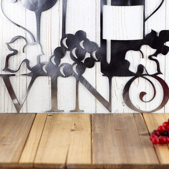 Close up of Vino on our wine metal wall art, in raw steel. Placed against a wood wall.