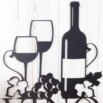 Close up of wine glasses, wine bottle, and grapes on our Vino metal wall art, in silver vein powder coat. 