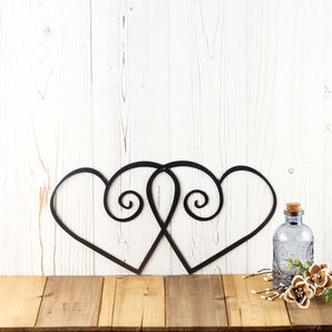 Hearts metal wall decor, in silver vein powder coat. Placed against a white wood wall.