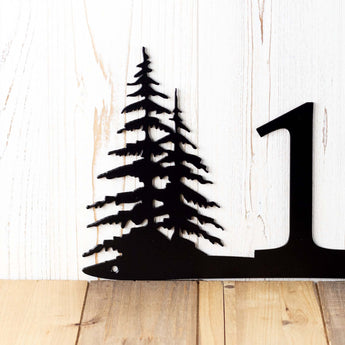 Close up of pine trees on our 2 digit metal house number sign, in matte black powder coat.